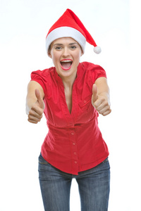 微笑出现拇指的圣诞帽的年轻女人