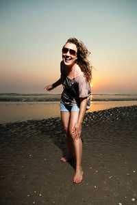 有在日落时在海滩上玩的棕色头发的漂亮女孩