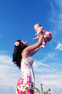在蔚蓝的天空，户外肖像投掷婴儿的母亲