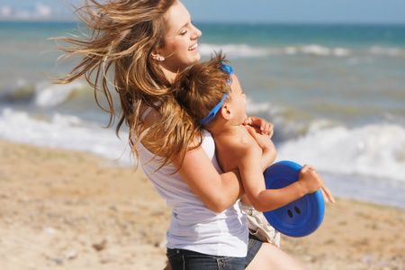 幸福的母亲和儿子在海滩上玩