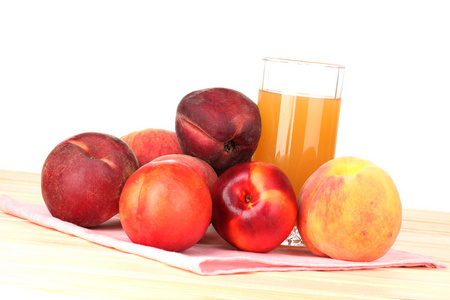 成熟的桃子和白色背景上的木桌上的果汁