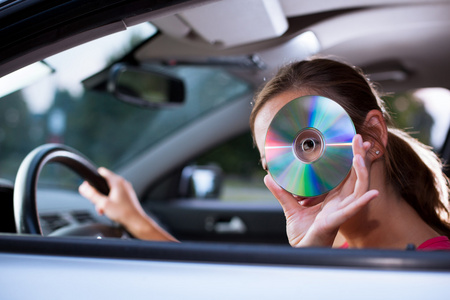 年轻的女司机在车里播放音乐更换CD