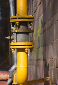 黄色燃气管道与棕色墙上的水龙头