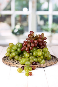 成熟的绿色葡萄上窗口背景上的木桌上的柳条摇篮
