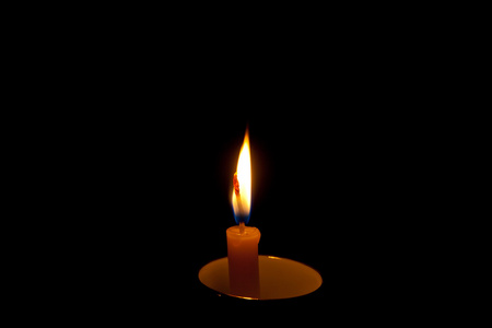 燃烧的蜡烛在黑暗中的瓷杯子