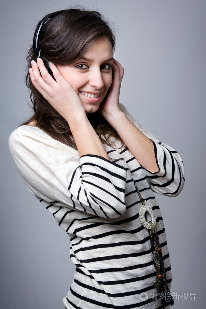 微笑的年轻女士在灰色背景听音乐