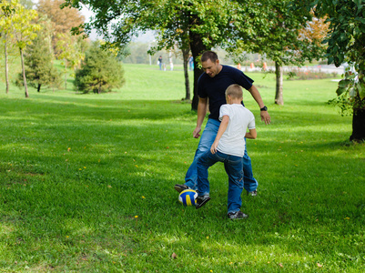 在与他的父亲踢足球的小男孩