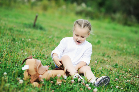 可爱的女孩玩玩具在草丛中的肖像