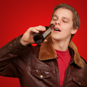 喝啤酒的红色背景下的年轻男子的画像
