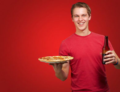 比萨饼和啤酒缓缴红色背景的年轻人的肖像