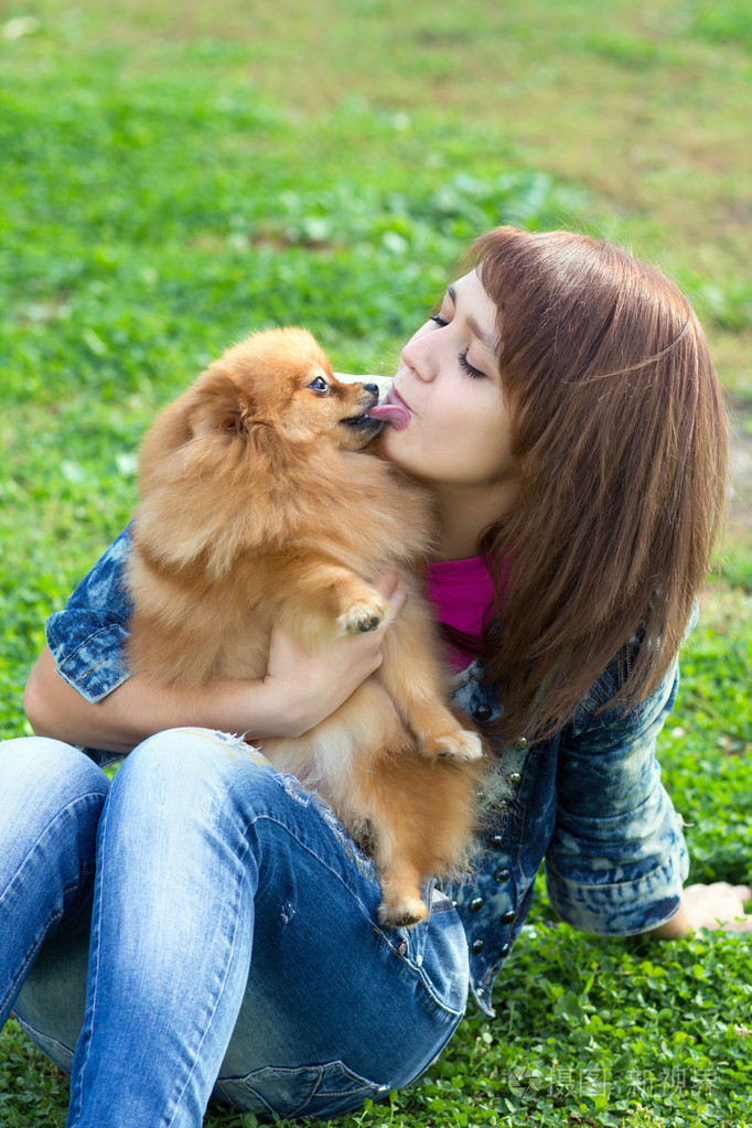 博美犬舔一个年轻女子的脸