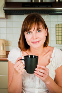 年轻女人，享受一杯咖啡在她家中