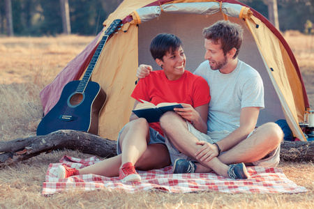 年轻夫妇露营和读一本书