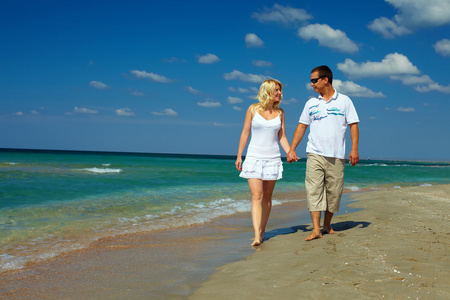 假日的浪漫,幸福沙滩上散步的情侣照片
