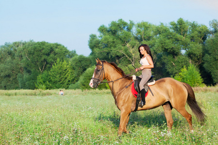 美丽的女孩骑着马在农村照片