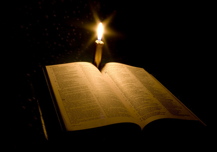 一本圣经打开与蜡烛的表上