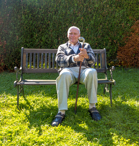 老人非常喜欢坐在长椅上在他的花园