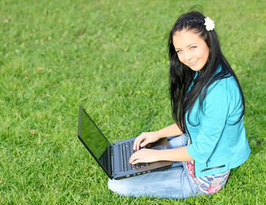 女人用的笔记本电脑的草地上