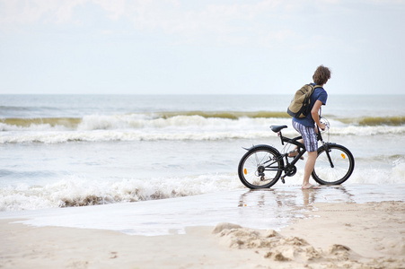 年轻男子骑自行车沿 al 海滩