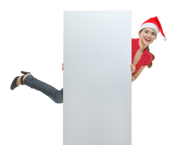 性格开朗年轻女子在持有空白广告牌的圣诞帽子