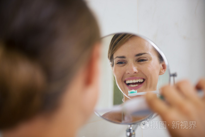 快乐的女人用电动牙刷刷牙