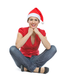 快乐的年轻女人在圣诞老人帽子坐在地板上