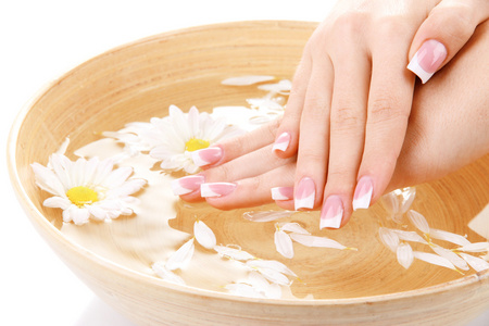 女人手与法国修指甲和用水竹碗里的花