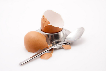 勺子与隔绝在白色背景上的 eggcup 鸡蛋的壳