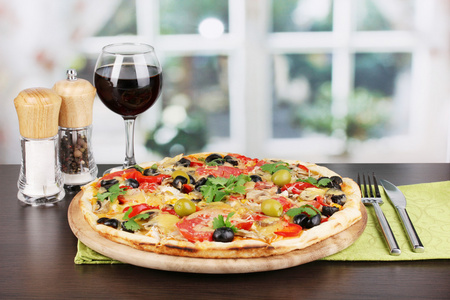 美味披萨用红酒和香料在窗口上的木桌上的玻璃