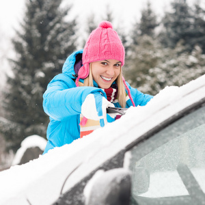 清洁汽车挡风玻璃的雪冬天的女人