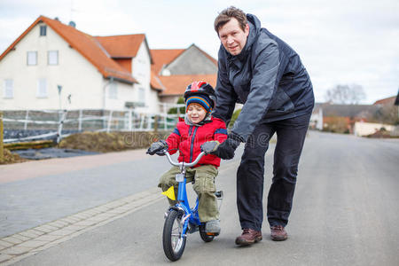 年轻的父亲教他3岁的小儿子骑自行车