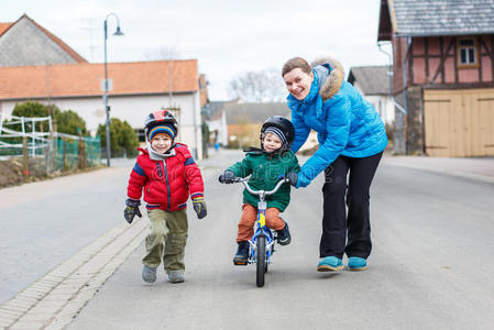 年轻的母亲教她两岁的小儿子骑自行车
