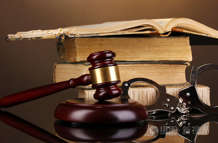 木槌, 手铐和棕色背景关于法律的书