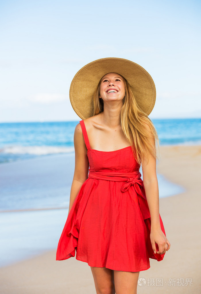 快乐美丽的女人在沙滩上的红裙子