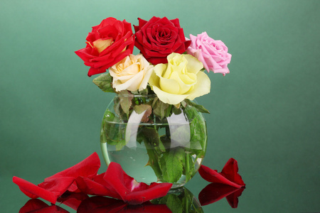 美丽的玫瑰在绿色背景上的玻璃花瓶