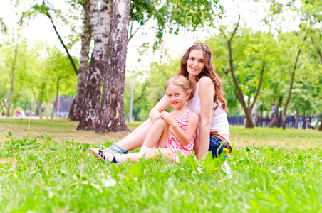 母亲和女儿一起坐在草地上