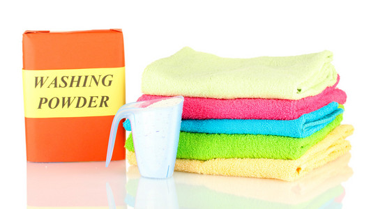 洗涤粉与兰色测量杯和毛巾，孤立在白色框中