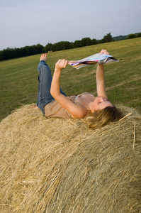 漂亮的女孩在农场上阅读杂志