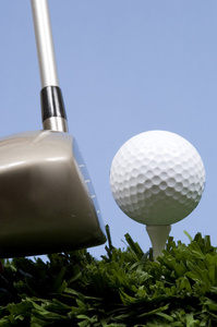 高尔夫球在球棒上三通与驱动程序的草地上
