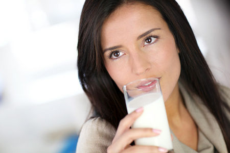 有魅力的年轻女人喝新鲜的牛奶
