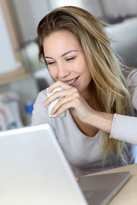 女人喝咖啡时检查的膝上型计算机上的电子邮件