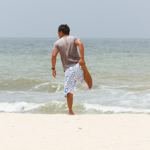 在南中国海上的海滩上拉伸的男人