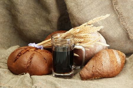坦卡的格瓦斯和黑麦面包用粗麻布背景上的耳朵