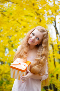 在秋天公园的礼物箱的红发女孩