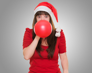 吹气球和戴着圣诞帽子的女人