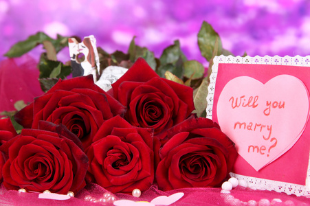 束美丽的玫瑰与情人节上粉红色织物上紫色背景特写