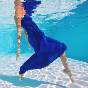 与蓝色的裙子在游泳池水下女人肖像