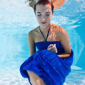 与蓝色的裙子在游泳池水下女人肖像