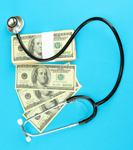 医疗成本的概念 听诊器和美元在蓝色背景