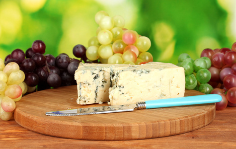 奶酪与葡萄上明亮的绿色背景上切板模